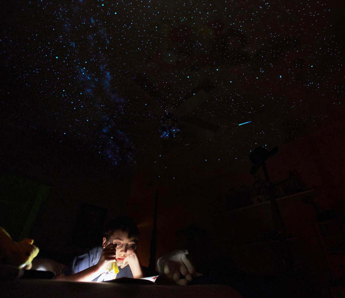 Boy reading under Night Sky Murals star ceiling